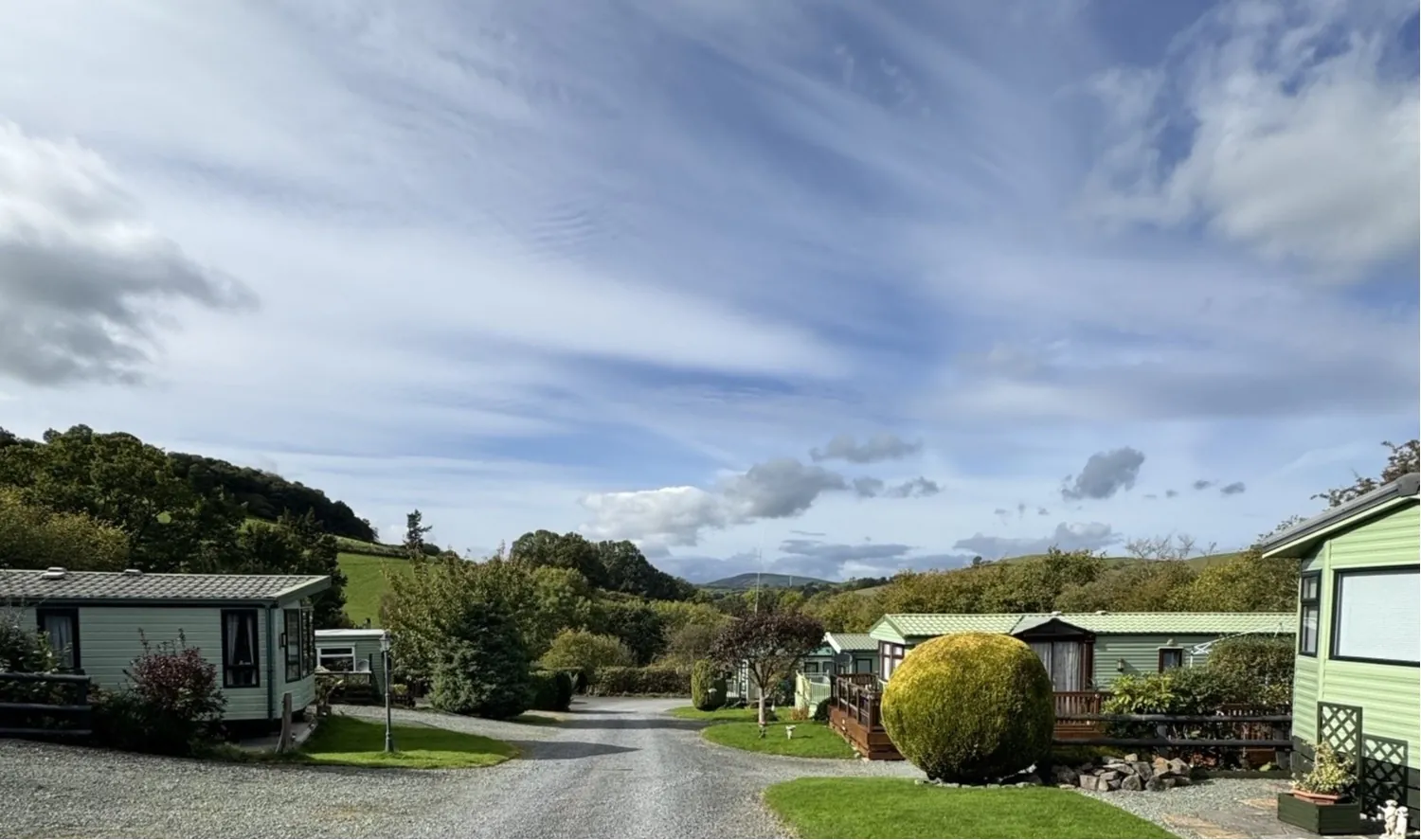 Holiday homes at Caerau Park with the Powys hills beyond under a wide blue sky