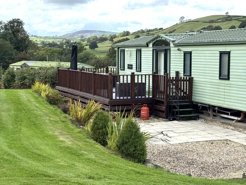 A holiday home with decking overlooking the lawns and hills at Caerau Park